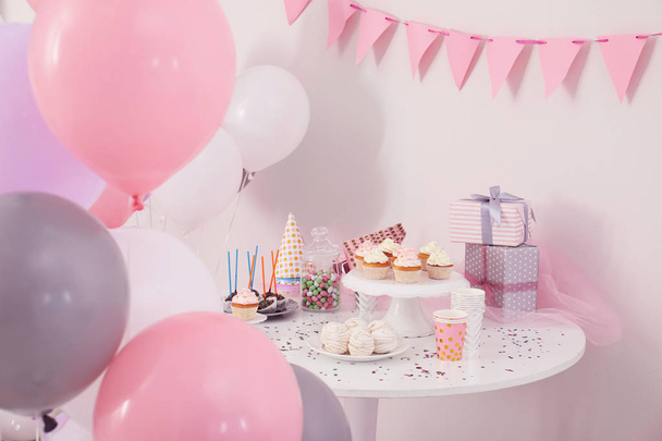 Party treats and items on table in room decorated with balloons - Fotó, kép