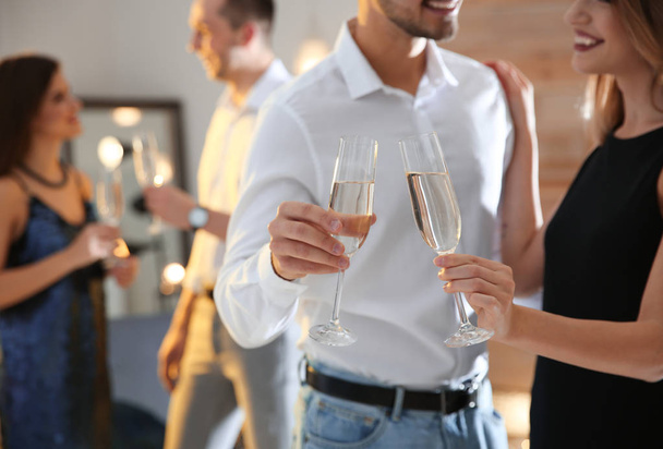 Счастливая пара с шампанским в бокалах устраивает вечеринку в помещении
 - Фото, изображение