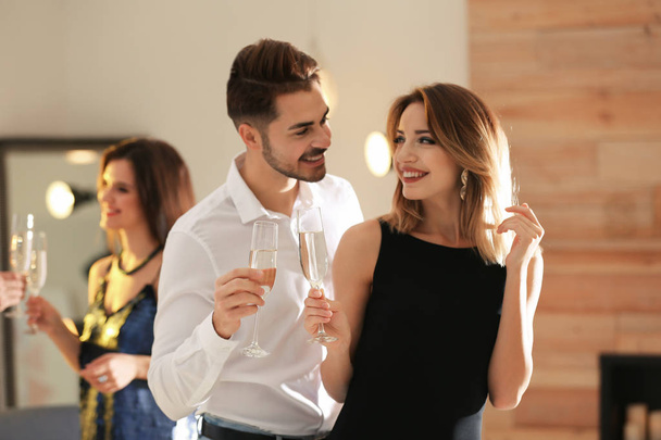 Happy couple with champagne in glasses having party indoors - Foto, Bild