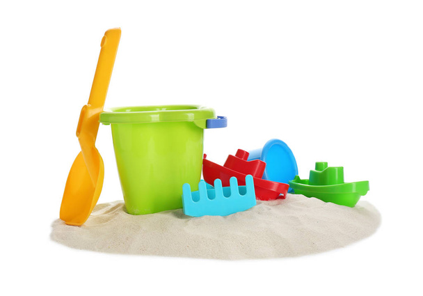 Plastic beach toys on pile of sand against white background - Foto, Imagen