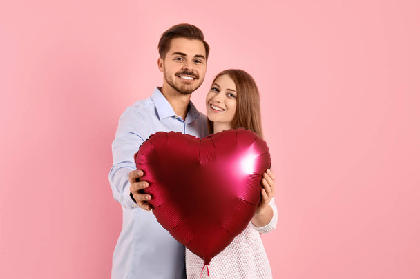 Portrait of man and woman with heart shaped balloon on color background - Foto, immagini