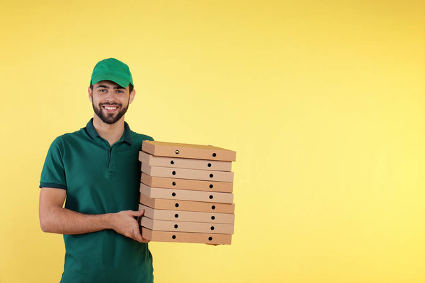 Young courier with pizza boxes on color background, space for text. Food delivery service - Φωτογραφία, εικόνα