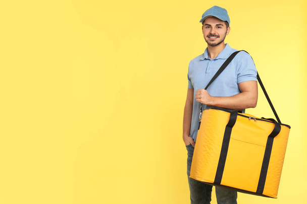Young courier with thermo bag on color background, space for text. Food delivery service - Photo, Image