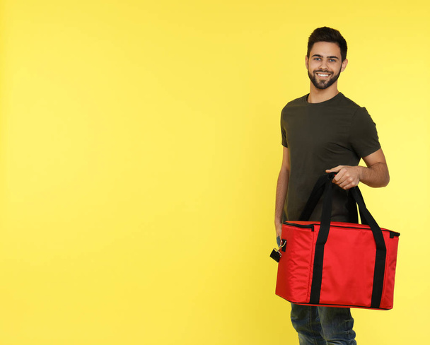 Young courier with thermo bag on color background, space for text. Food delivery service - Foto, Imagem