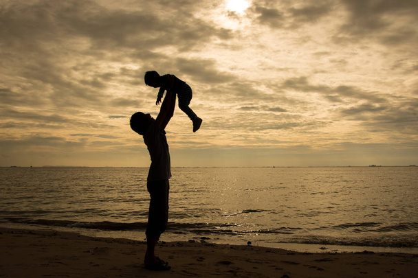 Apa és fia játszik a tengerparton naplemente idején. A barátságos családi fogalmát. - Fotó, kép
