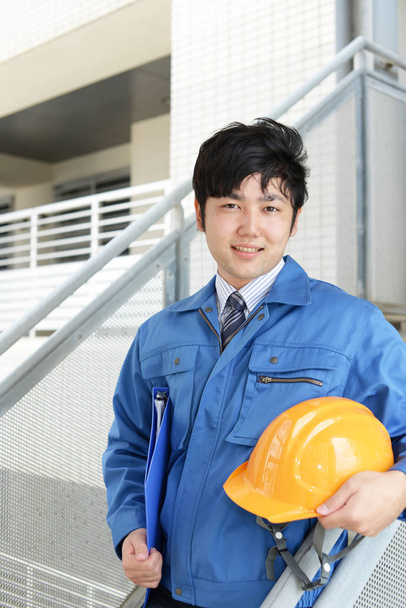 Sorridente lavoratore asiatico con un casco
 - Foto, immagini