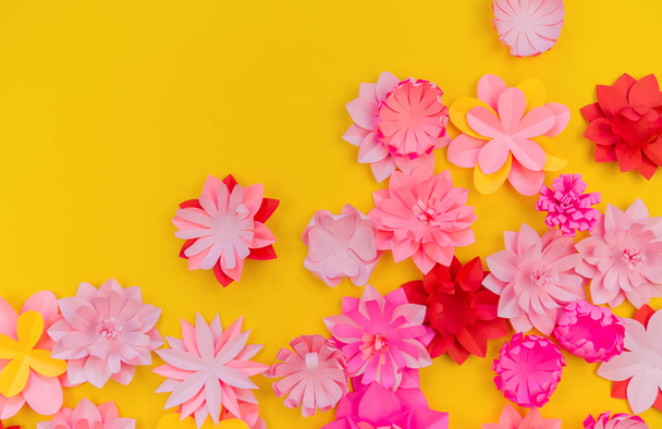 Flower made of coral color paper. The pink color of the curl and leaf. Yellow background. Handmade florist. Favorite hobby of fused applique. - Foto, afbeelding