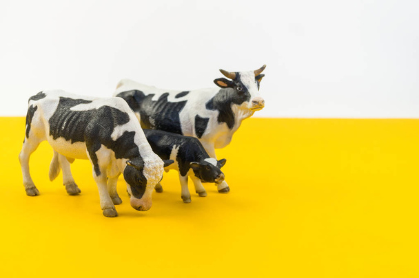 Toy cow made of plastic on a yellow background. Animal from the farm for the child. Pet artiodactyl. - Fotó, kép
