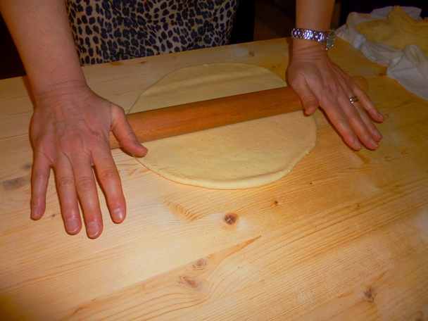 Női baker húzza ki a tésztát, az olasz tigelle a sodrófa a csomózott asztali főzés - Fotó, kép
