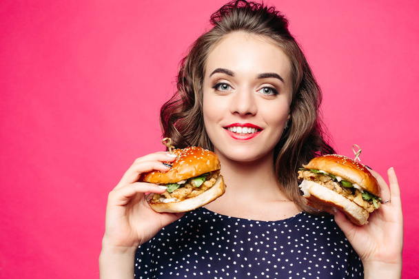 Chica de positividad sonriendo y posando con dos sabrosas hamburguesas
. - Foto, imagen