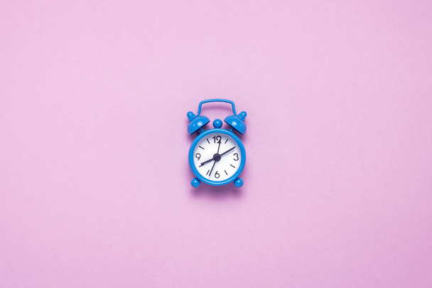 Reloj despertador azul sobre fondo rosa. Concepto día y noche, gestión del tiempo, planificación, horario de día y noche, minimalismo. Piso tendido, vista superior
 - Foto, imagen
