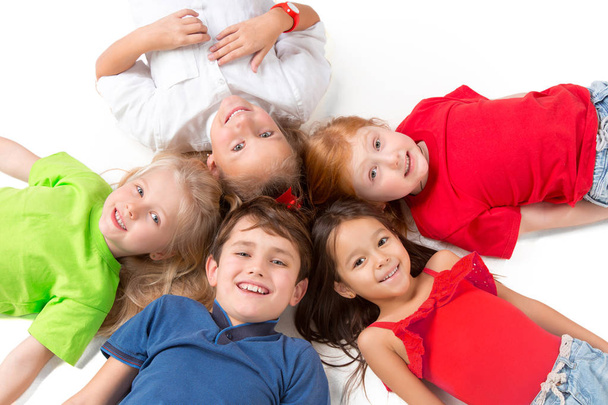 Close-up van gelukkige kinderen liggend op de vloer in de studio en opzoeken - Foto, afbeelding