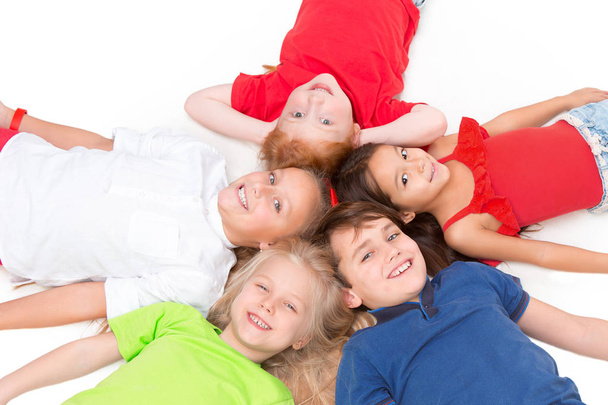 Close-up van gelukkige kinderen liggend op de vloer in de studio en opzoeken - Foto, afbeelding