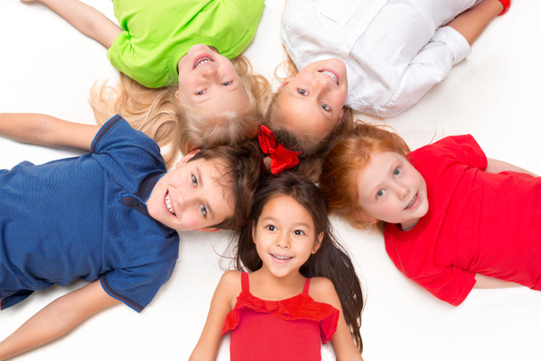 Close-up of happy children lying on floor in studio and looking up - Photo, Image