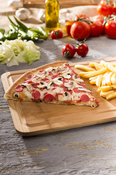 zblízka pohled italskou pizzu a hranolky na dřevěném prkénku - Fotografie, Obrázek