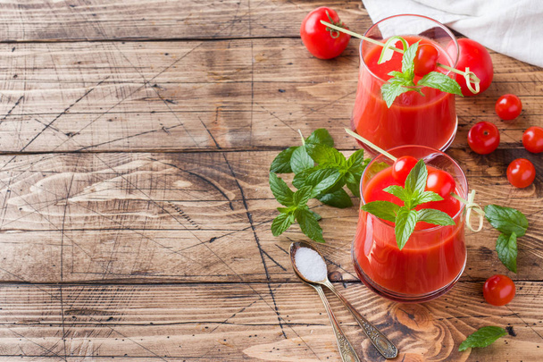 Tomato juice with mint in glass and fresh tomatoes on a wooden table. Healthy organic food concept. Copy space - Foto, Bild