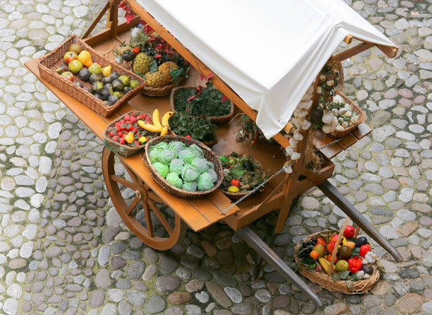 oude middeleeuwse groenteman kar met verse groenten en fruit te koop op straat - Foto, afbeelding