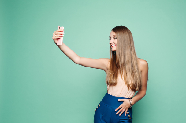 Jolie femme prenant selfie via téléphone portable sur fond vert. - Photo, image