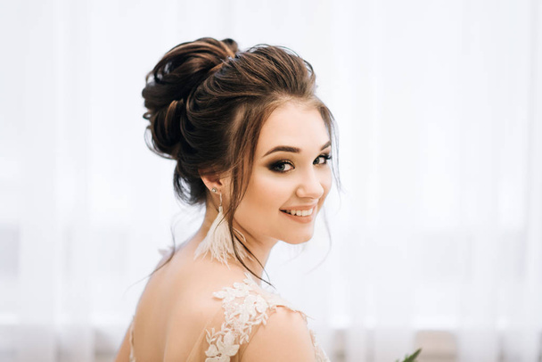 Pretty young girl.  Boudoir morning of the bride. Bride with luxurious hair and makeup. Accessories with feathers - Fotografie, Obrázek