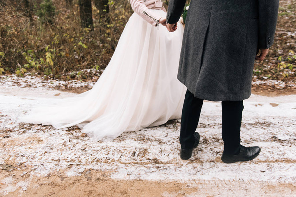Portret van gelukkige jonge pasgetrouwden liefdevolle. De bruid en bruidegom gaat u naar het steegje bos met de eerste sneeuw. Trouwdag - Foto, afbeelding