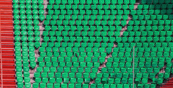 Пластиковые разноцветные места для зрителей в амфитеатре футбольного стадиона. Концептуальный фон пустых мест на стадионе
 - Фото, изображение