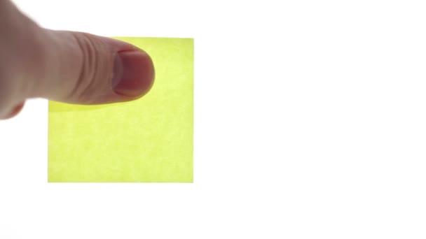 Man's hand zet lege gele sticker geïsoleerd op een witte achtergrond - Video