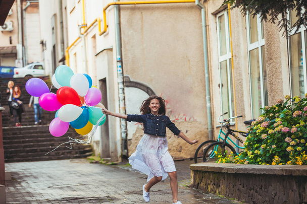 Girl with colorful balloons on the old town streets - Photo, Image