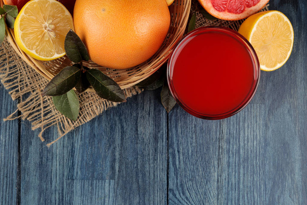 Citrus juices. grapefruit juice with fresh fruit on a blue wooden table. view from above. space for text - 写真・画像