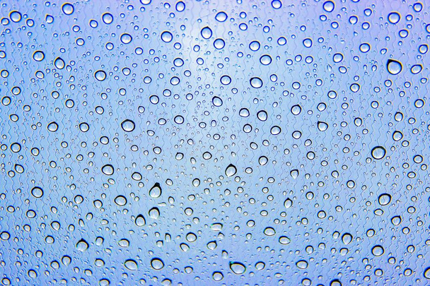 La pluie tombe sur le verre de la voiture. Fond bleu gris. Modèle de gouttes d'eau
 - Photo, image