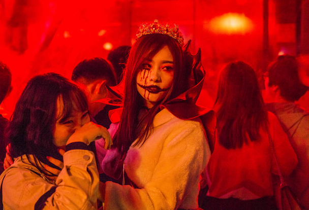 A young Chinese woman wearing zombie or demon costume and makeup takes part in a Halloween celebration on a bar street in Chengdu city, southwest China's Sichuan province, 31 October 2018. - Foto, afbeelding