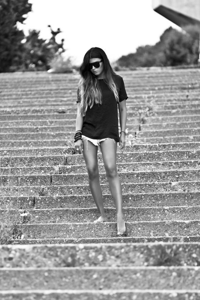 Young  beautiful girl in shorts and a  shirt is down the old stairs  - Φωτογραφία, εικόνα