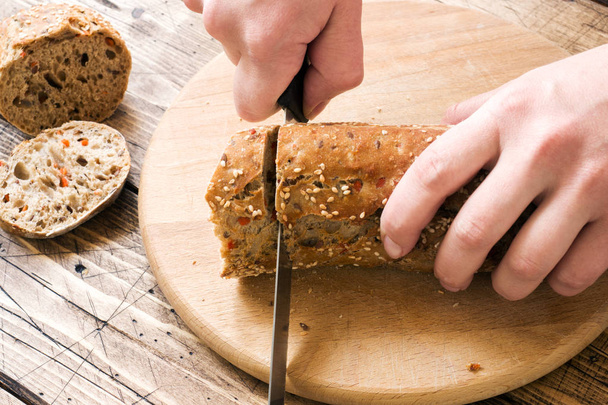 Pão fresco com sementes de girassol, sementes de gergelim e linho são cortados em pedaços em uma placa de corte
 - Foto, Imagem