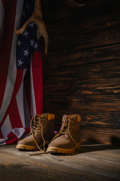 μπότες πεζοπορίας, κέρατα και αμερικανική σημαία σε ξύλινη επιφάνεια, ταξίδια έννοια  - Φωτογραφία, εικόνα