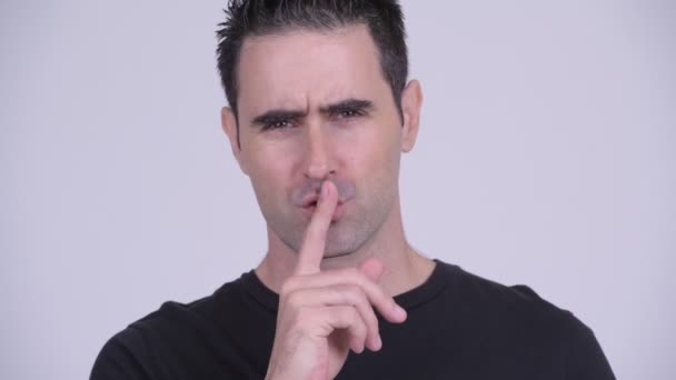 Gezicht van de knappe man met de vinger op de lippen tegen witte achtergrond - Video