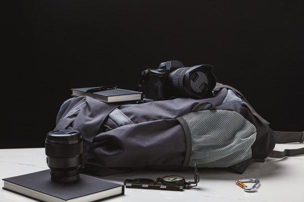 backpack, photo camera and trekking equipment on black - Φωτογραφία, εικόνα