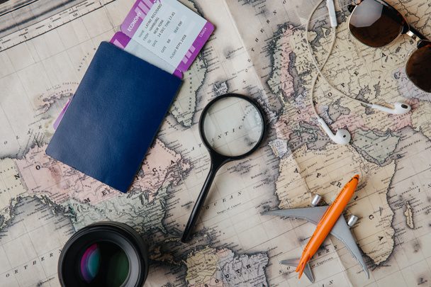 vue du dessus du passeport avec carte d'embarquement, lentille, loupe, écouteurs, lunettes de soleil et petit avion modèle sur la carte
 - Photo, image