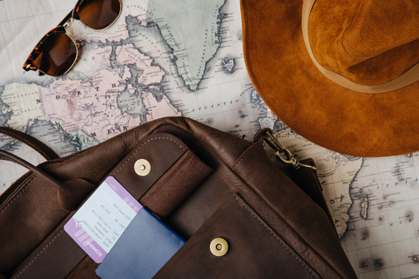 vista superior do saco de couro, passaporte, bilhete, óculos de sol, chapéu e mapa
 - Foto, Imagem