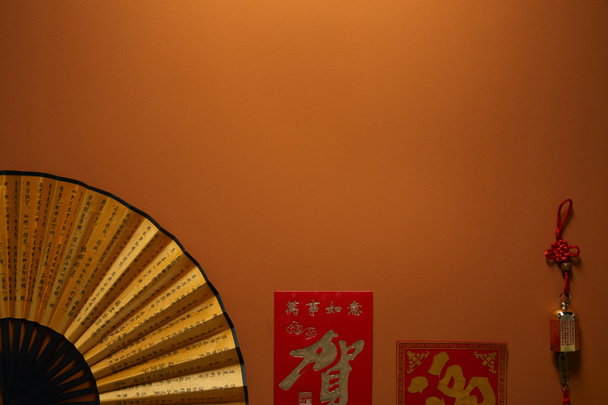 vista superior del ventilador con jeroglíficos sobre fondo marrón, composición de año nuevo chino
 - Foto, Imagen