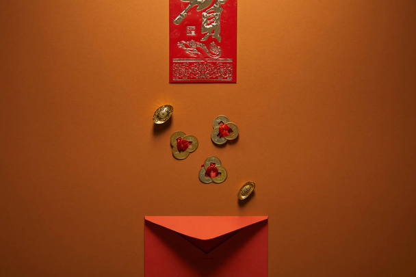 top view of red envelope, golden chinese decorations and hieroglyph on brown background - Fotografie, Obrázek
