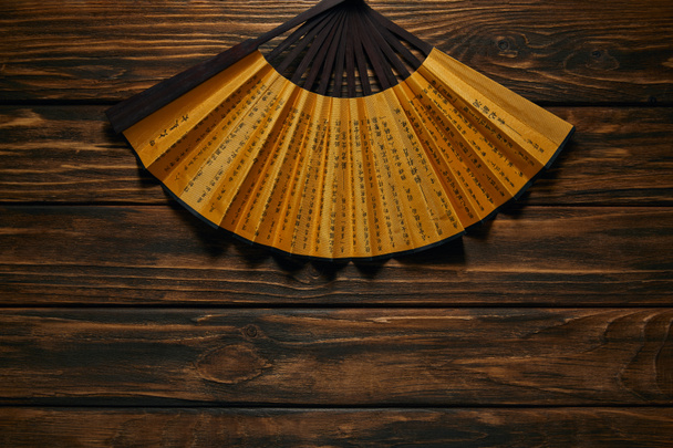 ahşap yüzey üzerinde hiyeroglifler ile dekoratif siyah ve altın fan üstten görünüm - Fotoğraf, Görsel
