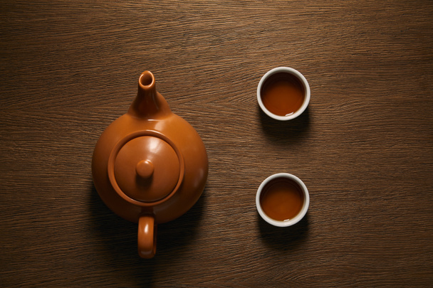vista dall'alto della teiera cinese in ceramica marrone e delle tazze di tè sul tavolo di legno
 - Foto, immagini