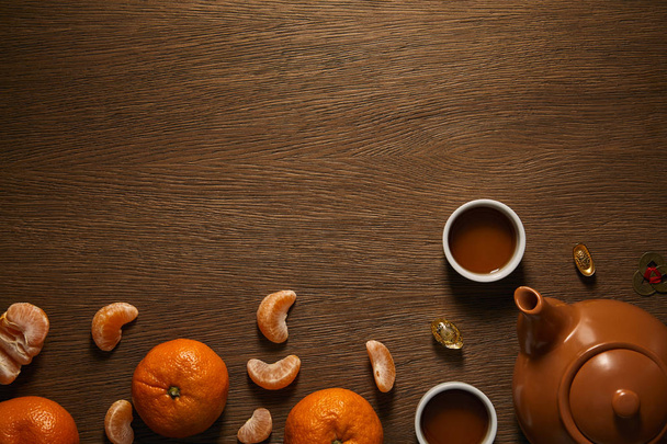 top view of tea set, tangerines and coins on wooden surface  - Foto, immagini