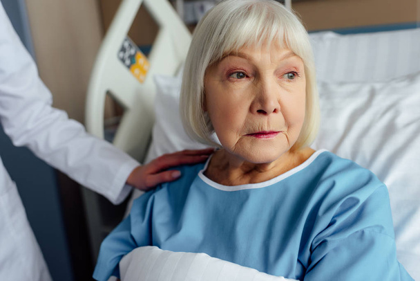female doctor consoling worried senior woman lying in hospital bed - Fotografie, Obrázek