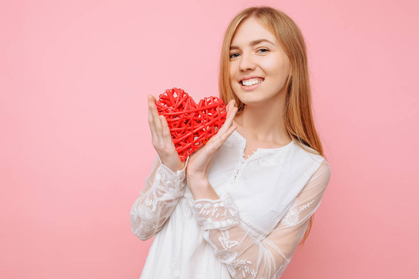 Menina bonita no amor segurando um coração vermelho, Valentine, em um fundo rosa
 - Foto, Imagem