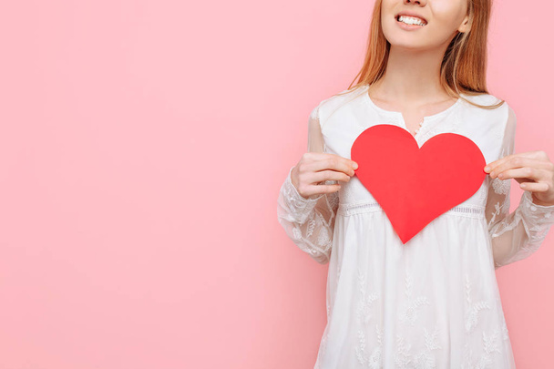 Beautiful girl in love holding a red heart, valentine, on a pink background - Fotoğraf, Görsel