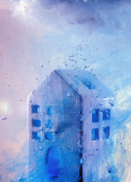 Small ceramic house under the water with violet acrylic paints. Fabulouse white ceramic house at the night with smoke from windows and doors. - Photo, Image