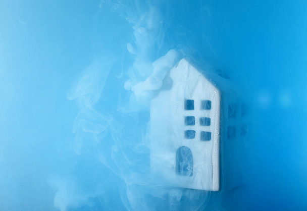 Small ceramic house under the water with blue acrylic paints. The concept of real estate, rent, sale or heating. White house from fairy tale. - Photo, Image