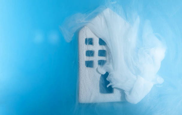 kleines Keramikhaus unter Wasser mit blauer Acrylfarbe. das Konzept der Immobilien, Miete, Verkauf oder Heizung. Weißes Haus aus dem Märchen. - Foto, Bild