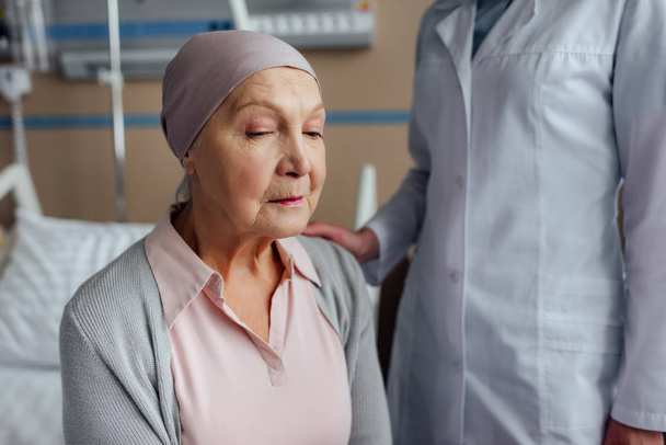 selective focus of doctor consoling senior woman with cancer in hospital - Photo, Image