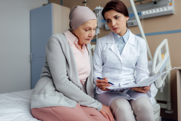 disgustada doctora que sostiene el diagnóstico y consulta a una mujer mayor con cáncer en el hospital
 - Foto, Imagen